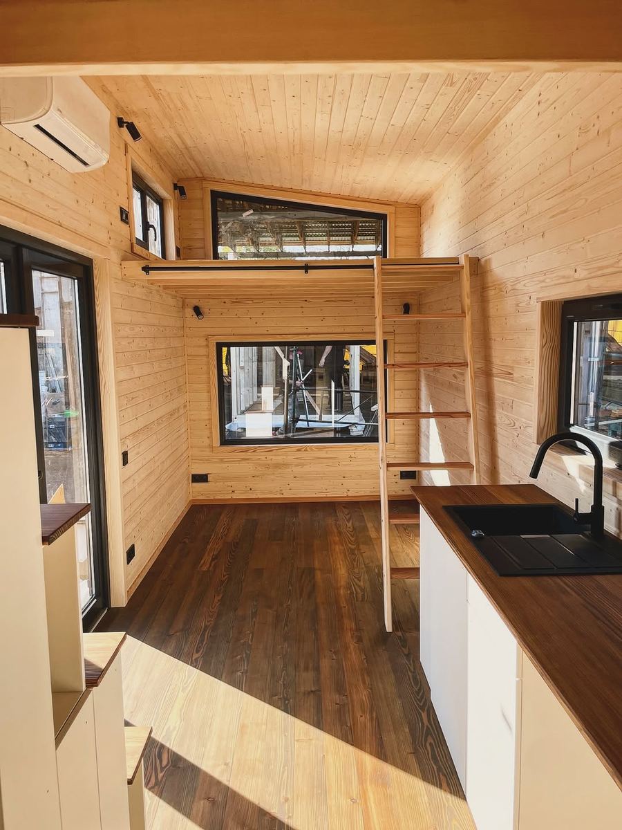 Tiny house interior — timber-lined living space with sleeping loft